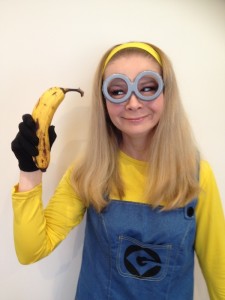 Lady dressed as a minion with minion at goggles on holding a banana for a minion party at Spellbound Parties
