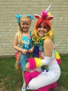 Lady dressed as rainbow unicorn with little girl in a My Little Pony dress